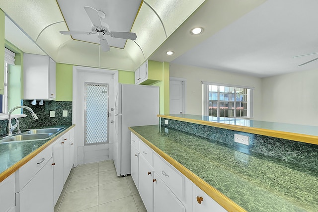 kitchen with sink, backsplash, white refrigerator, white cabinets, and light tile patterned flooring