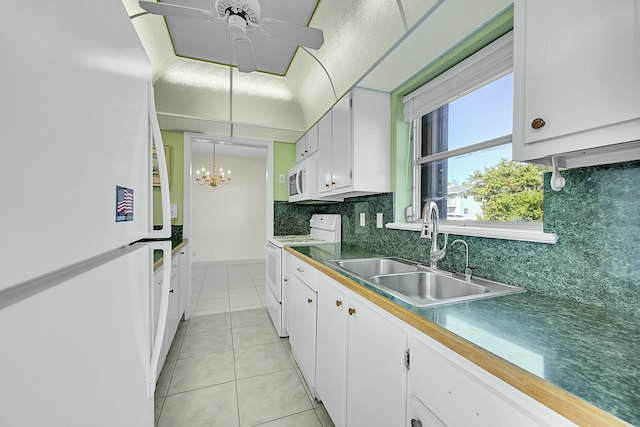 kitchen featuring light tile patterned flooring, white appliances, a sink, white cabinetry, and dark countertops