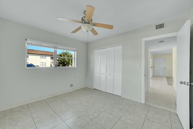 unfurnished bedroom with ceiling fan, light tile patterned floors, visible vents, baseboards, and a closet