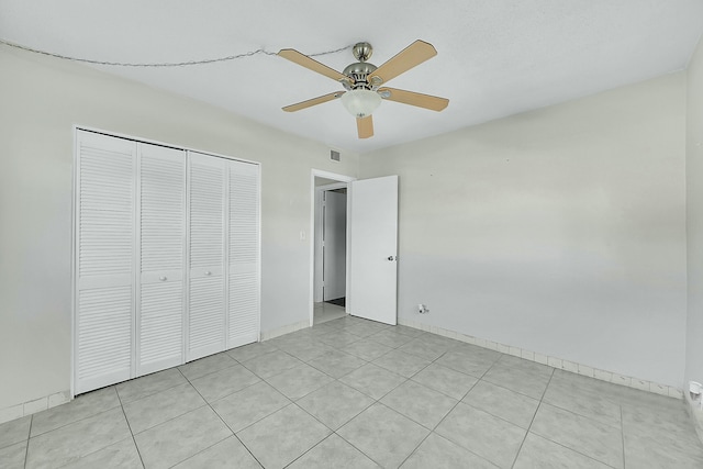 2110 NE 42nd St # 1B, Lighthouse Point, FL 33064 - unfurnished bedroom with a closet, a ceiling fan, light tile patterned floors, and baseboards