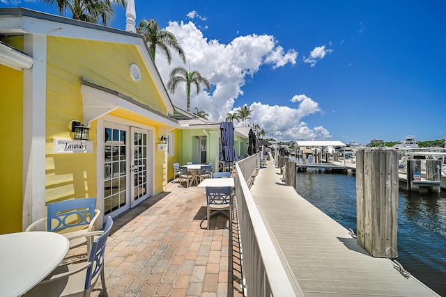 view of patio with a water view, a dock, and french doors