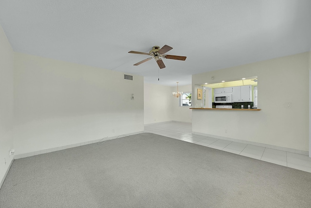 unfurnished living room featuring ceiling fan with notable chandelier, light carpet, visible vents, and light tile patterned floors