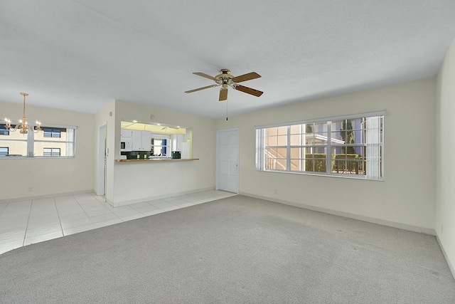 unfurnished living room with light carpet, light tile patterned floors, baseboards, and ceiling fan with notable chandelier