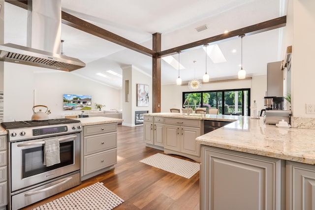 kitchen featuring vaulted ceiling with skylight, hanging light fixtures, island exhaust hood, light stone counters, and stainless steel appliances