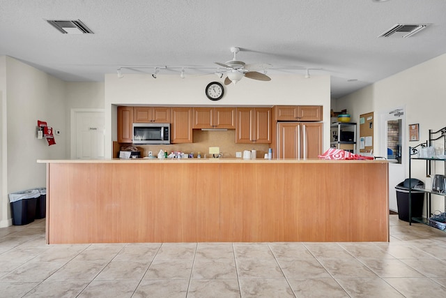 kitchen featuring light tile patterned flooring, ceiling fan, a textured ceiling, and paneled built in refrigerator