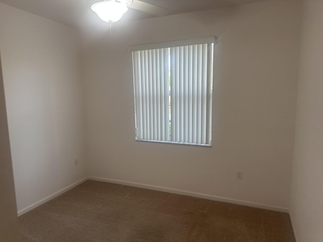 carpeted spare room featuring a ceiling fan and baseboards