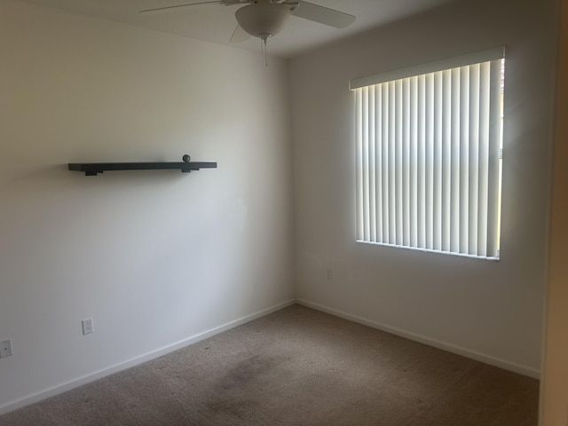 carpeted spare room featuring baseboards and a ceiling fan