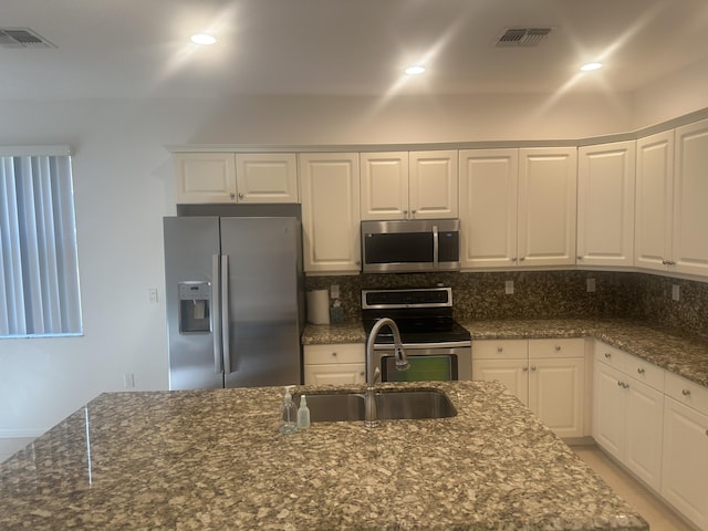 kitchen with appliances with stainless steel finishes, a sink, visible vents, and decorative backsplash