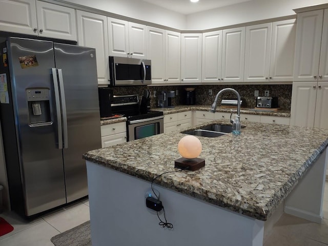 kitchen featuring light stone counters, light tile patterned flooring, stainless steel appliances, a sink, and decorative backsplash