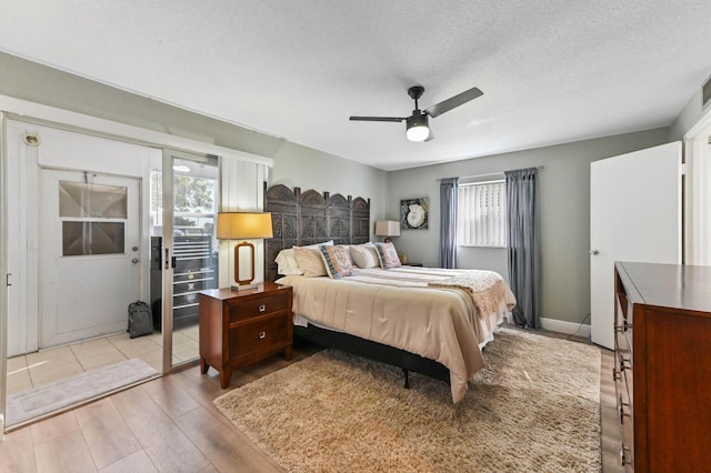 bedroom with multiple windows, ceiling fan, light hardwood / wood-style flooring, and a textured ceiling