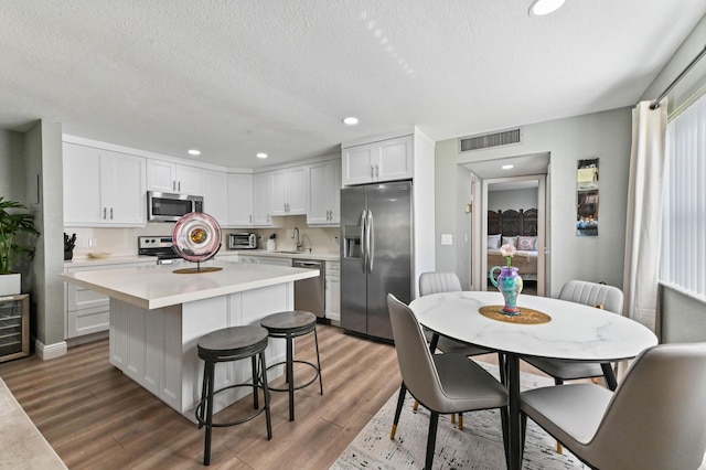 kitchen with sink, a breakfast bar area, a kitchen island, stainless steel appliances, and white cabinets