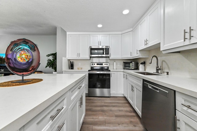 kitchen featuring sink, a textured ceiling, appliances with stainless steel finishes, dark hardwood / wood-style floors, and white cabinets