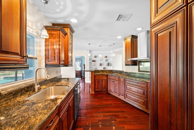 kitchen featuring sink, decorative light fixtures, dark stone counters, and wall chimney exhaust hood