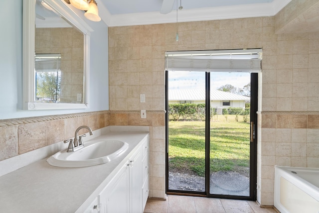 bathroom with tile walls, plenty of natural light, ornamental molding, a bath, and vanity