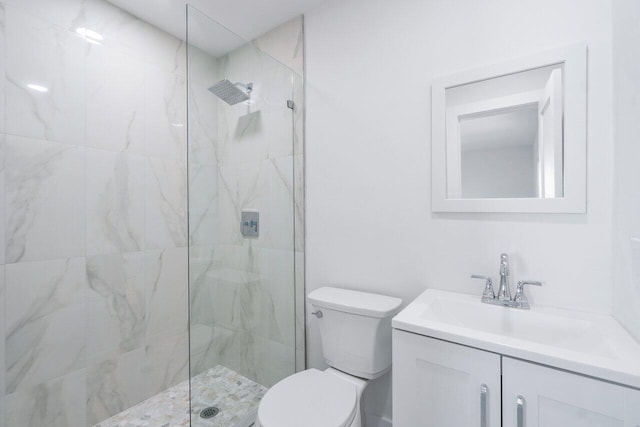 bathroom featuring a tile shower, vanity, and toilet