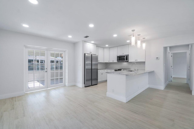 kitchen featuring white cabinetry, stainless steel appliances, french doors, decorative light fixtures, and kitchen peninsula