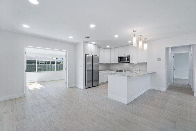 kitchen featuring white cabinetry, backsplash, hanging light fixtures, kitchen peninsula, and stainless steel appliances