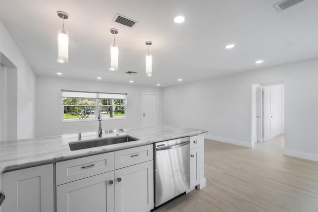 kitchen featuring light stone counters, stainless steel dishwasher, decorative light fixtures, and sink