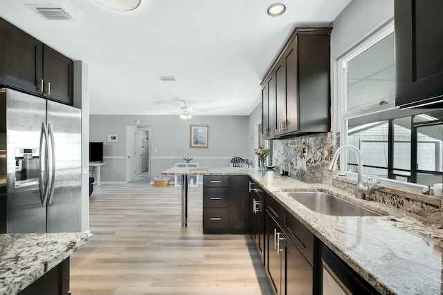 kitchen featuring sink, light hardwood / wood-style flooring, stainless steel fridge, dark brown cabinets, and light stone countertops