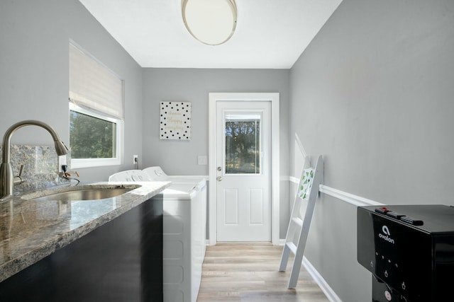 laundry room featuring sink, washing machine and clothes dryer, and light wood-type flooring