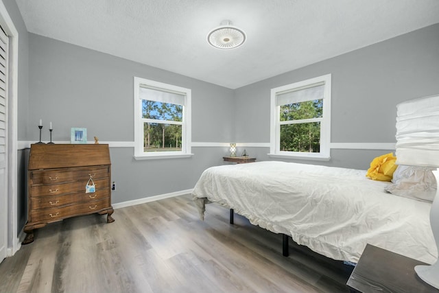 bedroom featuring hardwood / wood-style flooring, multiple windows, and a textured ceiling