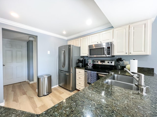 kitchen featuring sink, dark stone countertops, white cabinetry, stainless steel appliances, and light wood-type flooring