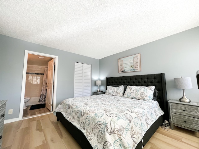 bedroom featuring ensuite bathroom, light hardwood / wood-style flooring, a textured ceiling, and a closet