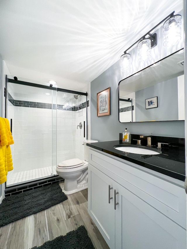 bathroom with vanity, hardwood / wood-style floors, toilet, and an enclosed shower