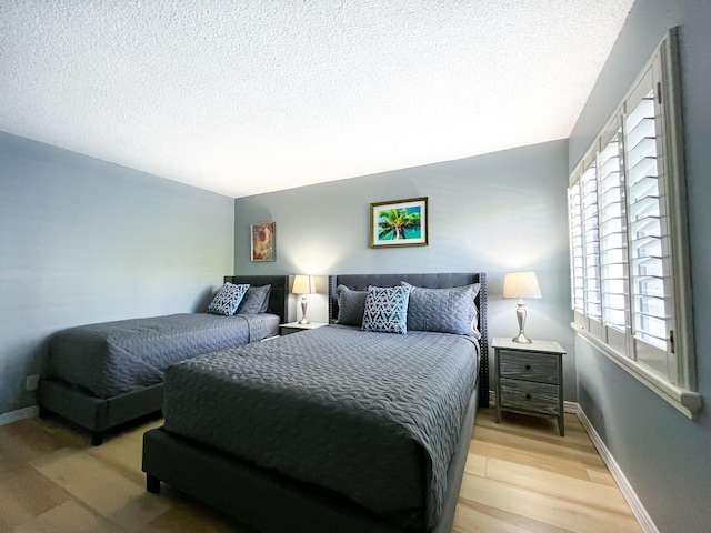 bedroom with a textured ceiling and light wood-type flooring