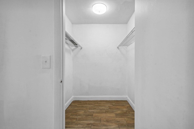 walk in closet with dark wood-type flooring