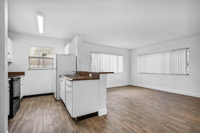 kitchen with white cabinetry, plenty of natural light, black range with electric cooktop, and hardwood / wood-style flooring