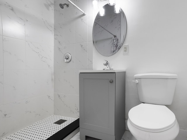 bathroom with vanity, toilet, and a tile shower