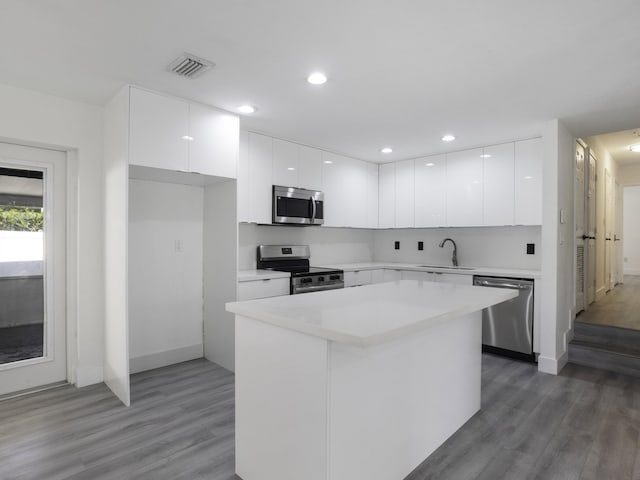 kitchen with a kitchen island, appliances with stainless steel finishes, sink, and white cabinets