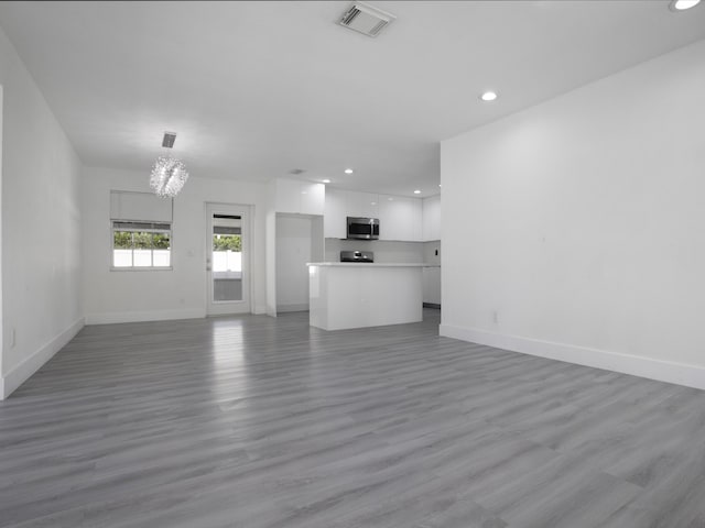 unfurnished living room featuring hardwood / wood-style floors and an inviting chandelier