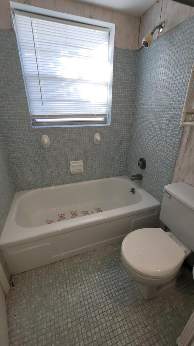 bathroom featuring tile patterned flooring, tiled shower / bath, and toilet