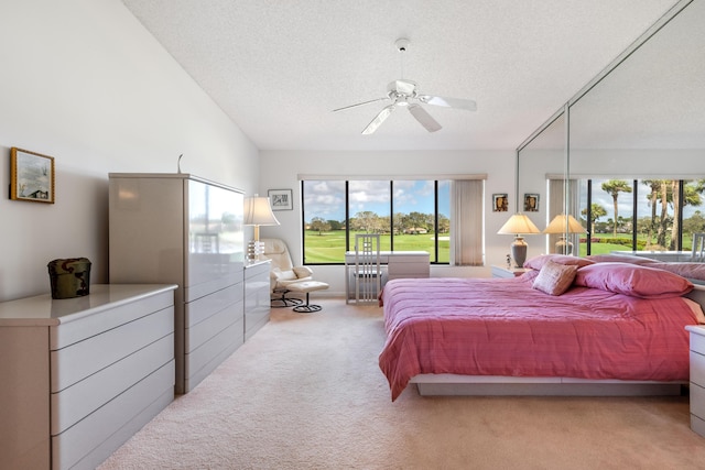 carpeted bedroom with ceiling fan, vaulted ceiling, and a textured ceiling