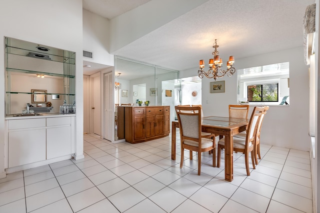 tiled dining room featuring a textured ceiling and a chandelier