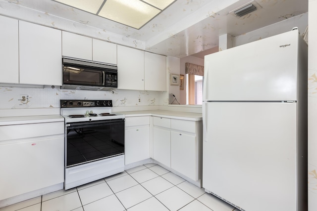 kitchen with light tile patterned flooring, white cabinets, and white appliances