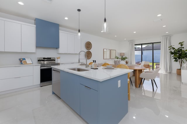 kitchen with pendant lighting, sink, white cabinets, a kitchen island with sink, and stainless steel appliances