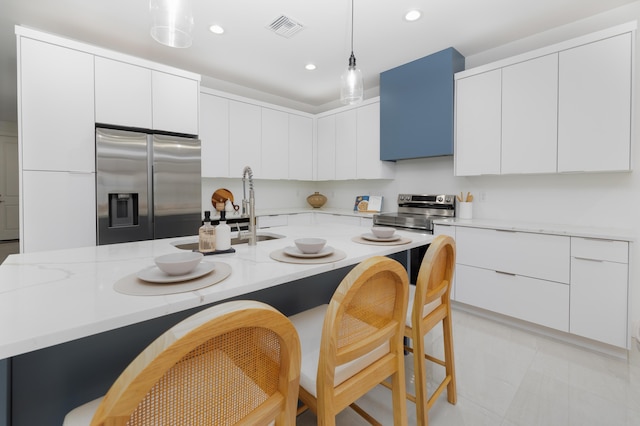 kitchen featuring pendant lighting, stainless steel appliances, white cabinets, and a center island with sink