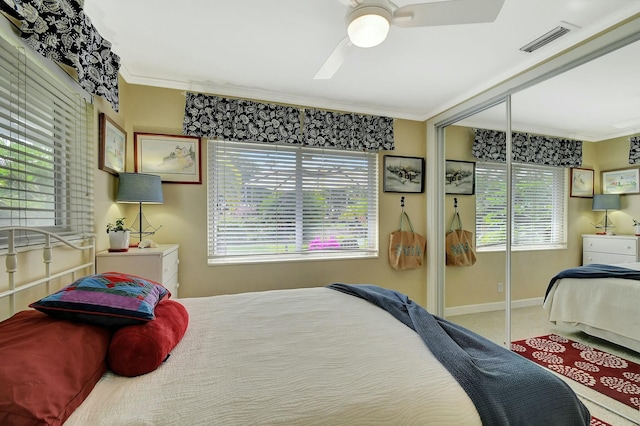 carpeted bedroom featuring crown molding, a closet, and ceiling fan