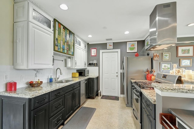 kitchen featuring appliances with stainless steel finishes, island range hood, white cabinetry, sink, and light stone countertops