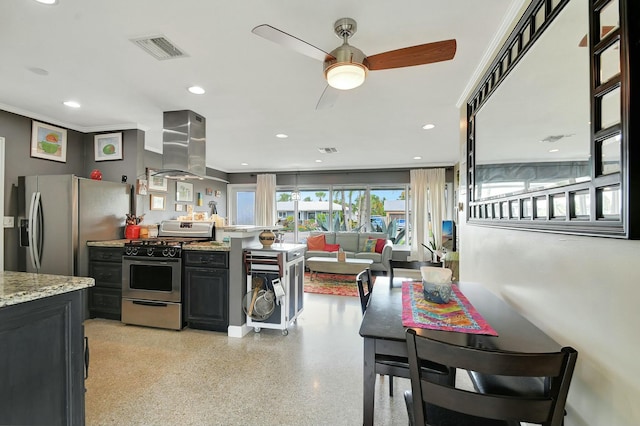 kitchen with island range hood, appliances with stainless steel finishes, ornamental molding, ceiling fan, and light stone countertops