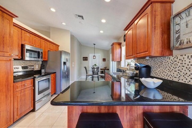 kitchen with lofted ceiling, light tile patterned floors, a breakfast bar area, stainless steel appliances, and tasteful backsplash