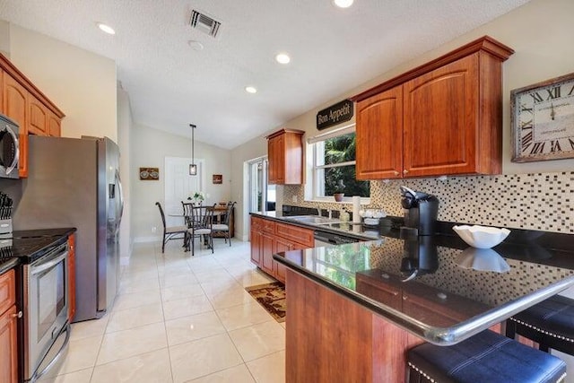 kitchen with lofted ceiling, light tile patterned floors, hanging light fixtures, stainless steel appliances, and decorative backsplash