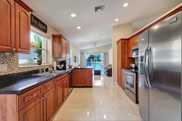 kitchen with lofted ceiling, tasteful backsplash, light tile patterned floors, appliances with stainless steel finishes, and kitchen peninsula