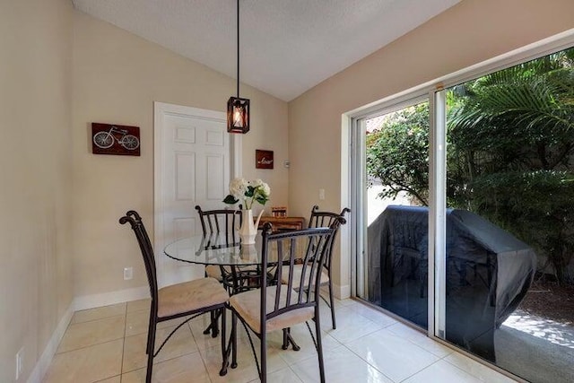 dining space featuring vaulted ceiling and light tile patterned flooring