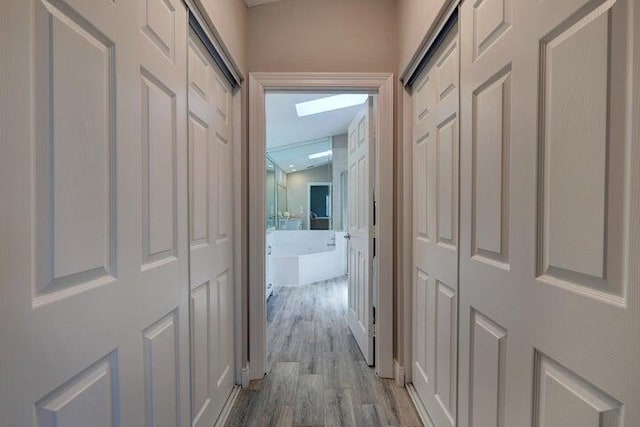 hall featuring lofted ceiling and light hardwood / wood-style floors