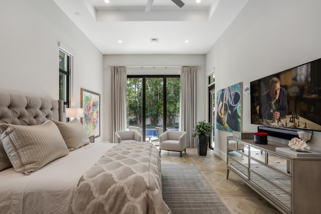 bedroom with access to exterior, a tray ceiling, and light parquet floors