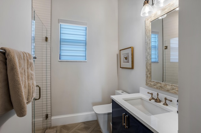 bathroom with parquet floors, vanity, an enclosed shower, toilet, and a healthy amount of sunlight